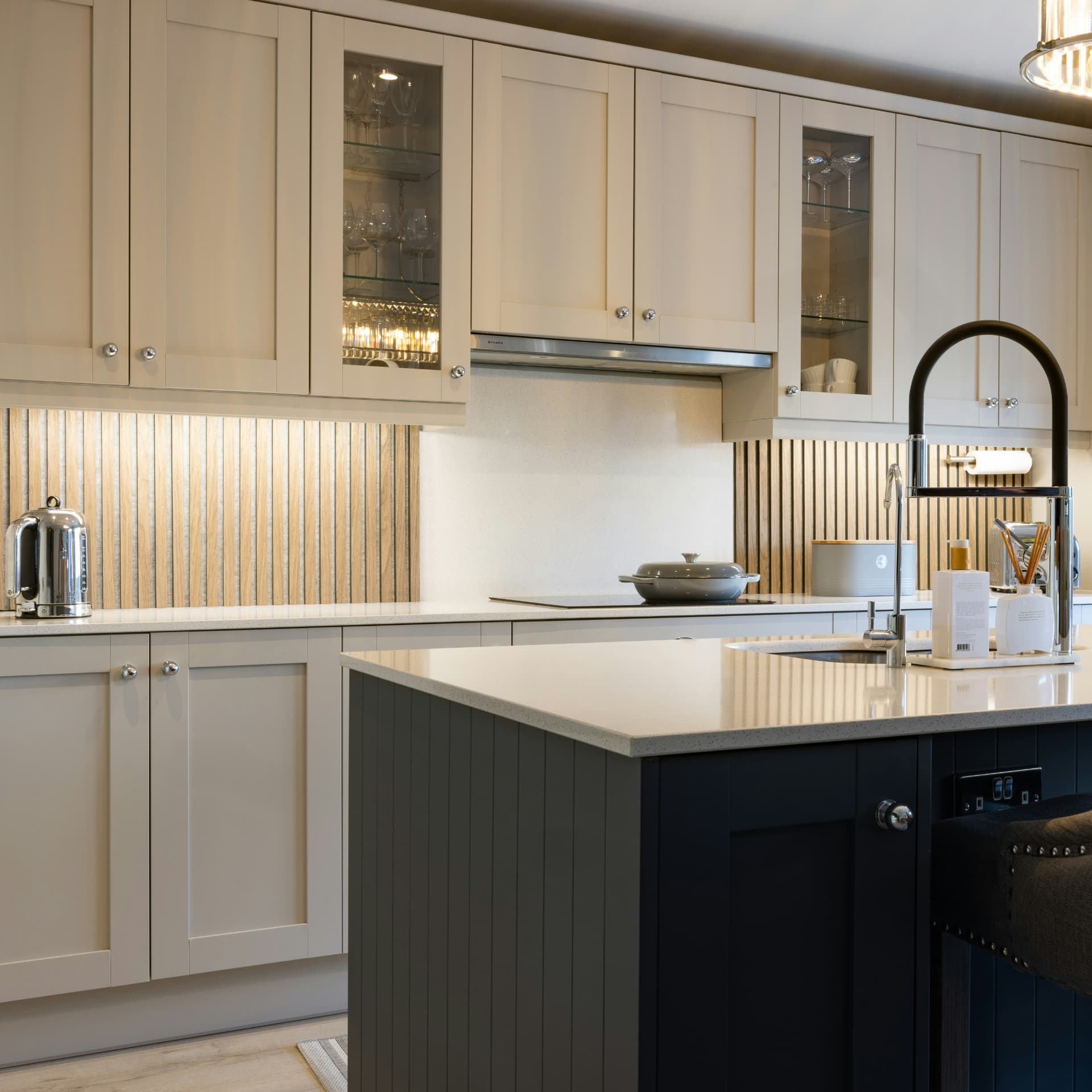 Cream shaker-style custom kitchen cabinets with glass-front uppers and a dark contrasting island